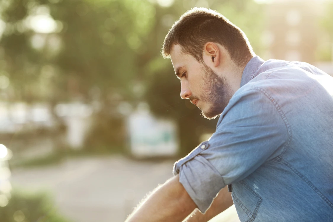 Mann steht drau&szlig;en und guckt auf den Boden